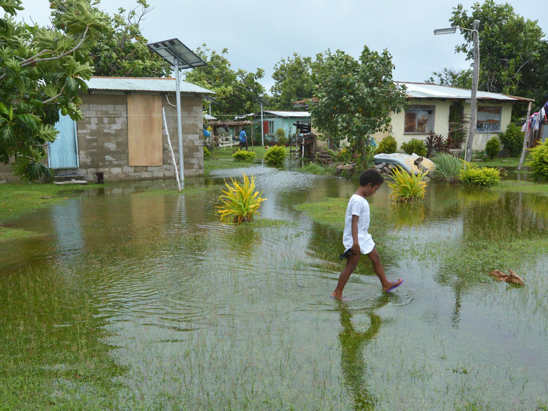 Indigenous Fijian girl walking on flooded land after Tropical Cyclone Winston.