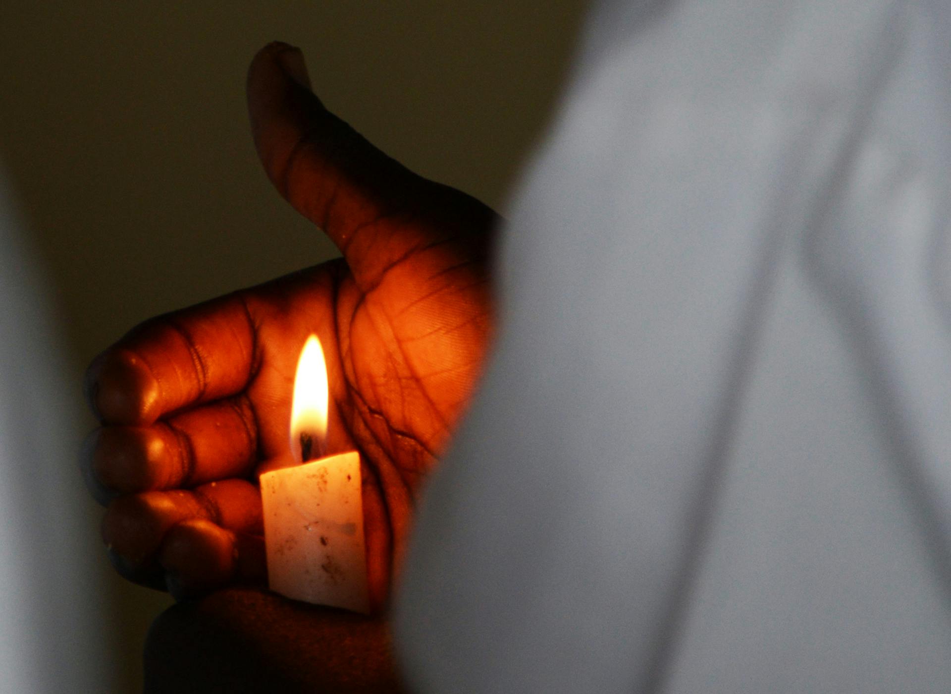 A burning candle being held by an acolyte in a Christian chapel in Kakuma refugee camp.