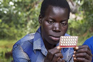 A Ugandan woman examines a pack of birth control pills.