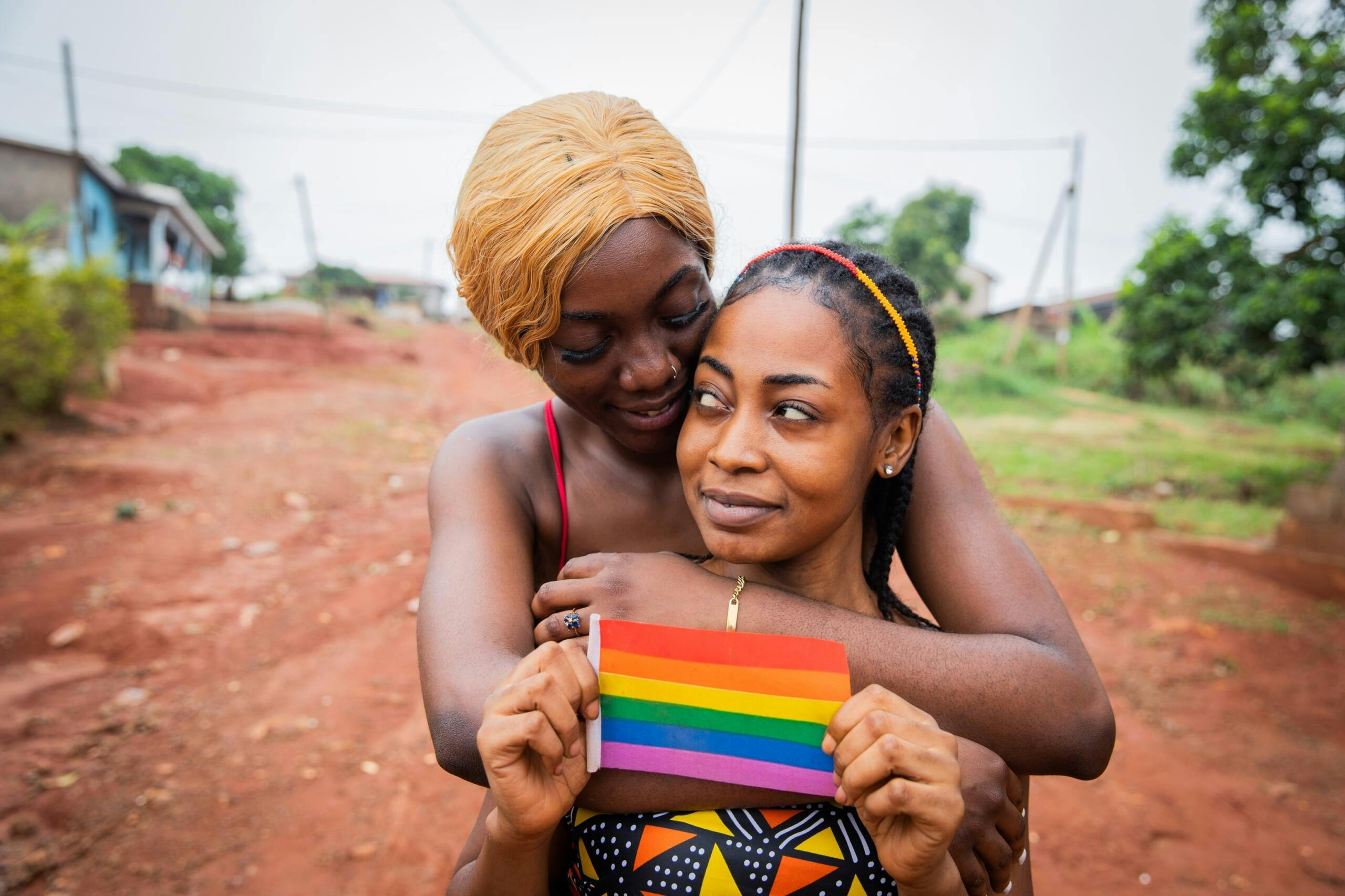 African,Lesbian,Women,Couple,Hugging,,Girlfriend,Holds,A,Rainbow,Flag,